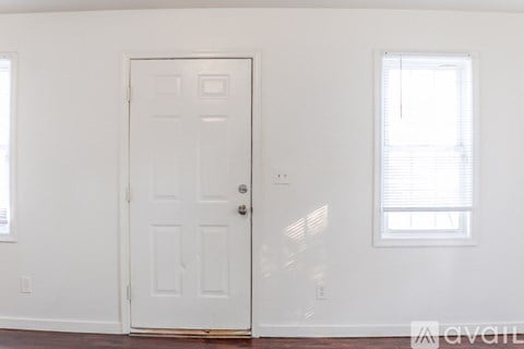 A white door is in a room with a window.