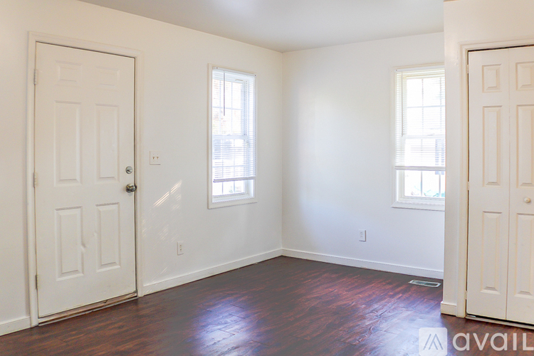 A room with two windows and a wooden floor.
