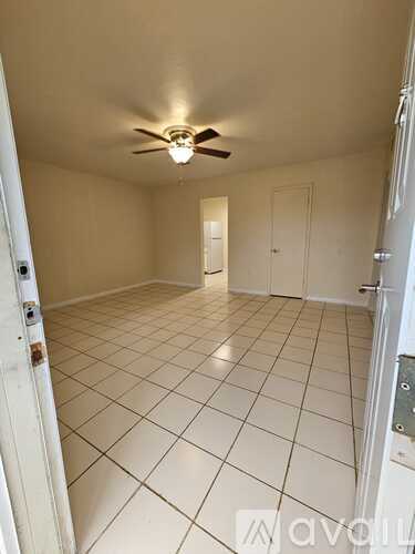 A room with a ceiling fan and tile flooring.