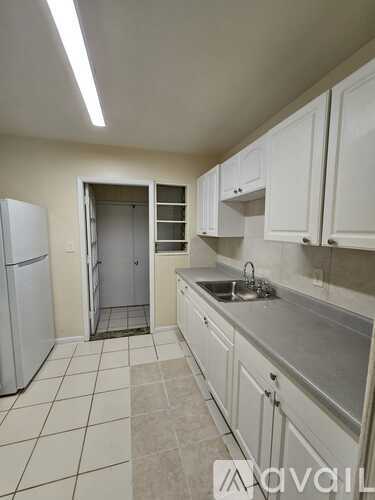 A kitchen with white cabinets and a white refrigerator.