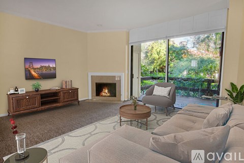 A living room with a fireplace and a painting of a bridge on the wall.
