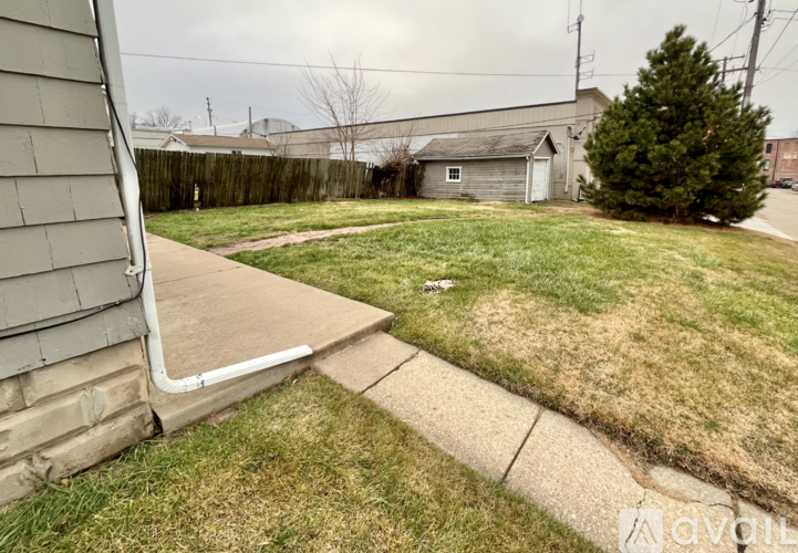 A backyard with a concrete walkway leading to a small shed.
