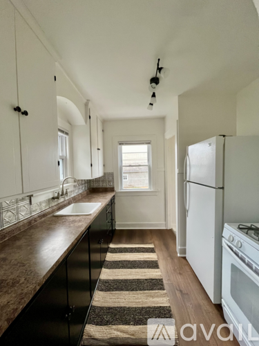 A kitchen with white appliances and a striped rug on the floor.