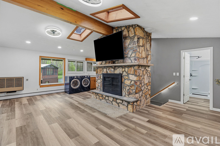 A modern living room with a stone fireplace and a flat screen TV mounted above it.