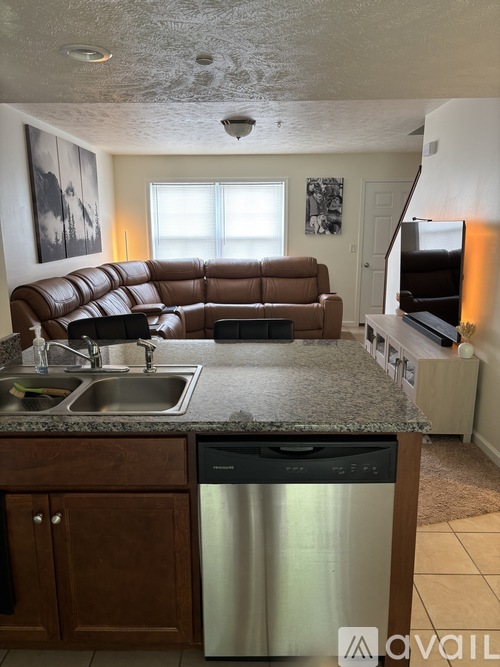 A kitchen with a brown leather couch and a granite countertop.