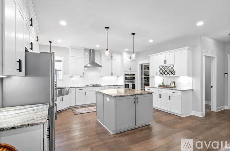 A modern kitchen with white cabinets and a marble countertop.