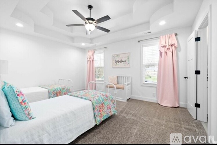 A bedroom with a white bed and a pink curtain.