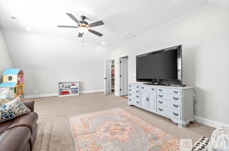 A living room with a brown couch and a television on a white cabinet.