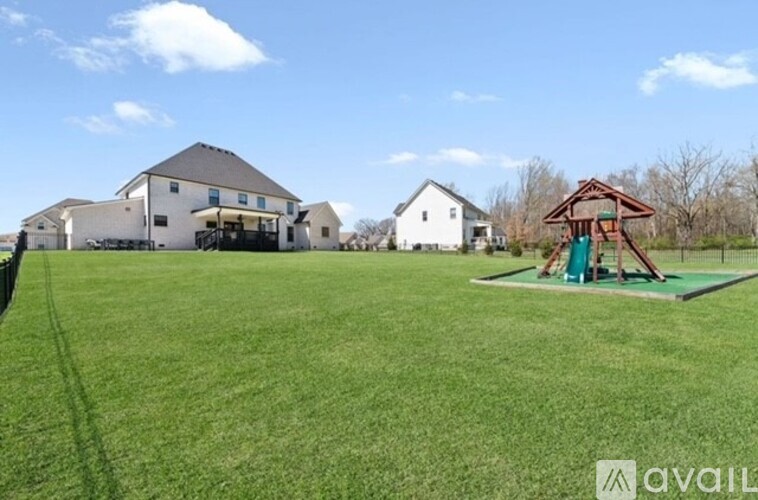 A large white house with a playground in the front yard.