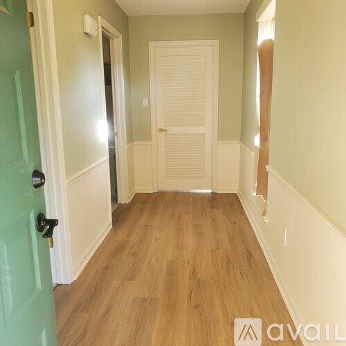 A hallway with a green door and a white door.