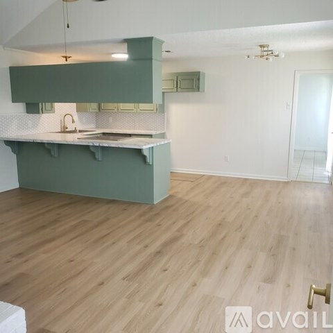 A kitchen with green cabinets and a wooden floor.