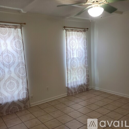 A room with a ceiling fan and patterned curtains.
