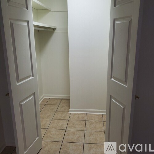 A hallway with white doors and tiled flooring.