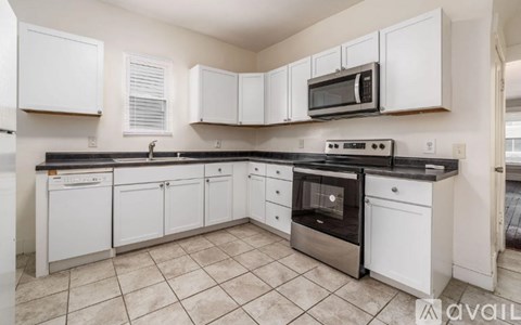 A kitchen with white cabinets and black countertops.