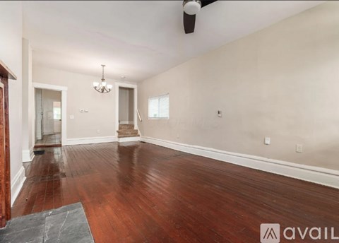 A spacious room with wood flooring and a chandelier.