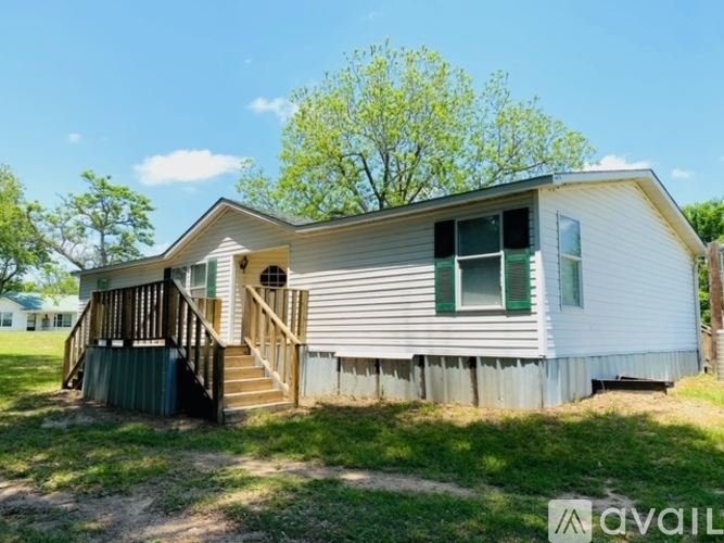 A house with a porch and a tree in the background.
