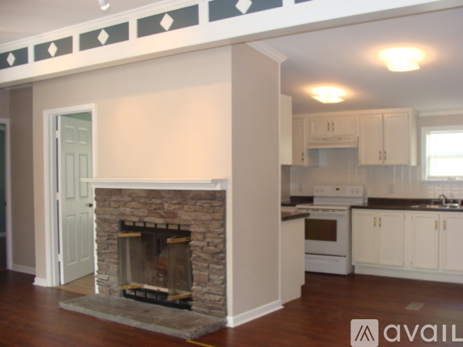 A stone fireplace in a room with wooden floors.