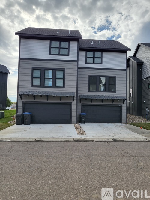 A two-story house with a grey and white exterior and two garages.