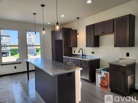 A modern kitchen with dark brown cabinets and a large island.