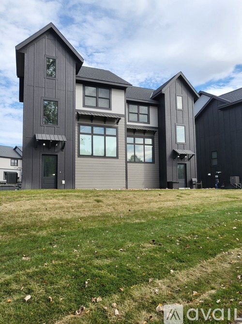 A modern house with a grey exterior and a large front yard.