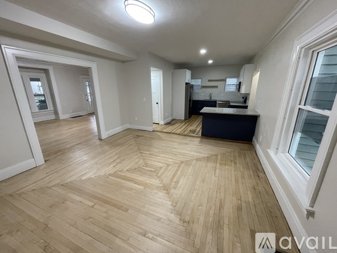 A spacious room with wooden flooring and white walls.
