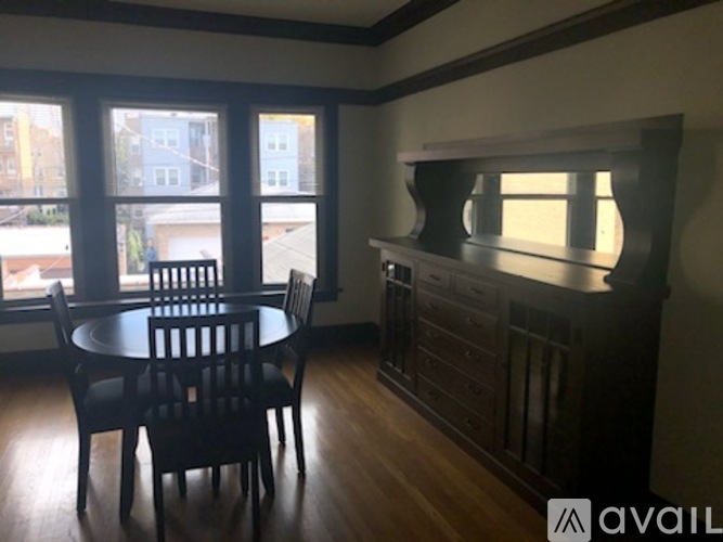 A dining room with a table and chairs and a cabinet.