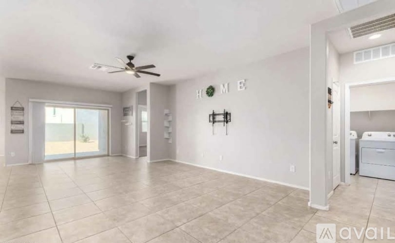 A spacious living room with a ceiling fan and a wall with the word HOME on it.