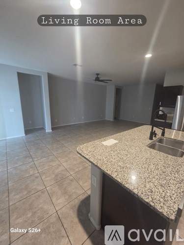 A living room area with a kitchen counter and a fan on the ceiling.