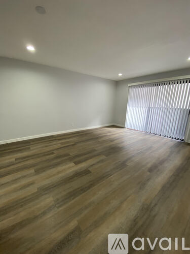 A room with wooden flooring and a window with blinds.