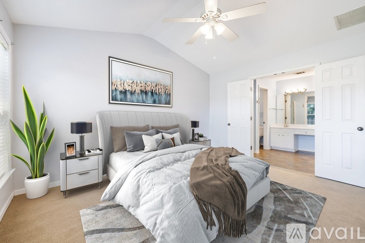 A bedroom with a large bed, a ceiling fan, and a plant.