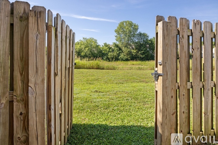A wooden fence with a gate stands in front of a grassy field.