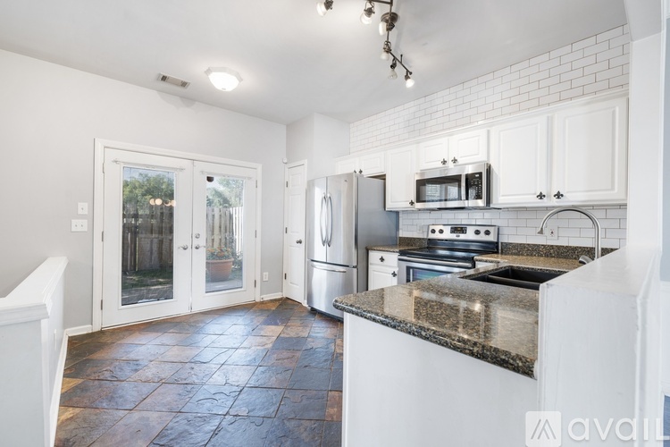 A kitchen with white cabinets and a black tile floor.
