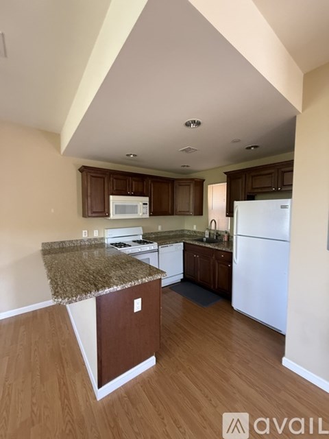 A kitchen with a granite counter top and wooden cabinets.