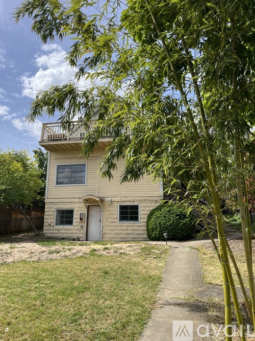 A house with a balcony and a tree in front.
