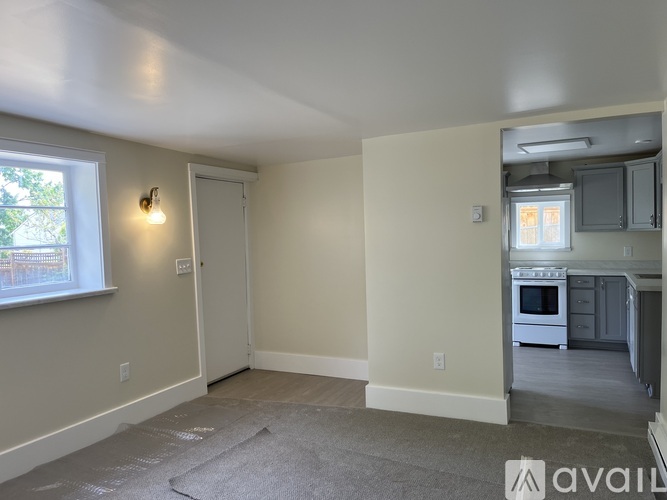 A room with a window and a door leading to a kitchen.