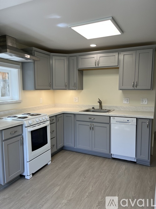 A kitchen with a white stove top oven and a white dishwasher.