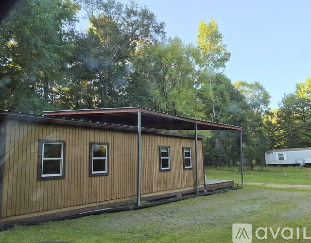 A wooden cabin with a porch is surrounded by trees.