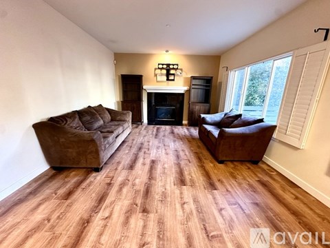 A living room with a brown couch and a fireplace.