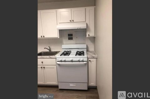 A white kitchen with a stove and sink.
