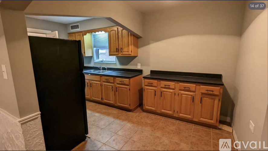 A kitchen with wooden cabinets and a black refrigerator.