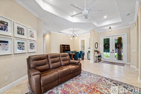 A living room with a brown leather couch and a ceiling fan.