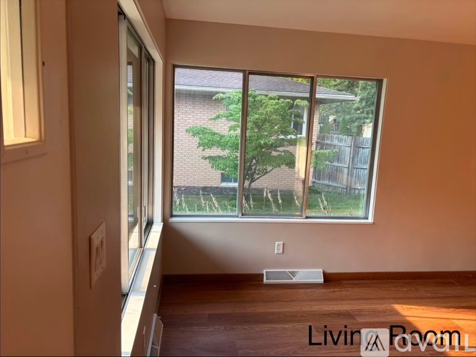 A room with a window overlooking a backyard.