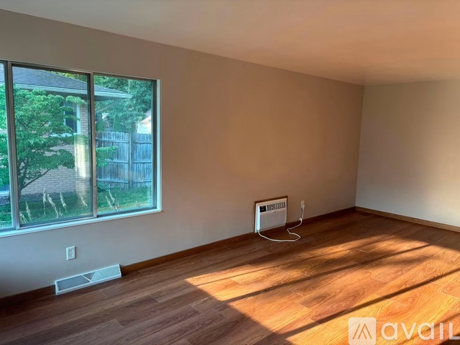 A room with wooden flooring and a window showing an outdoor view.