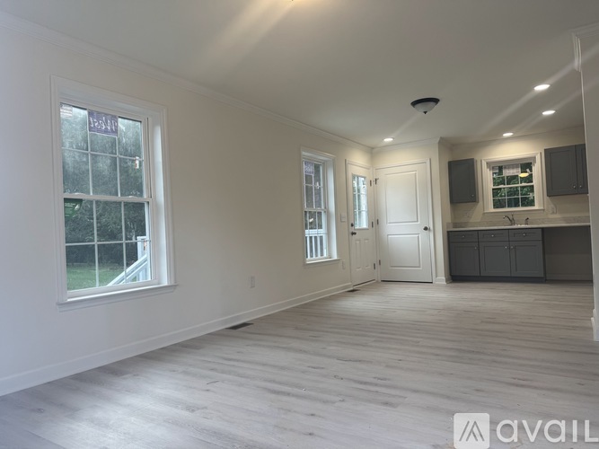 A spacious room with wooden flooring and white walls.