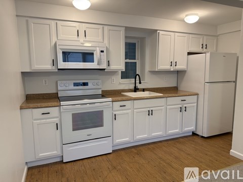 A kitchen with white cabinets and appliances.