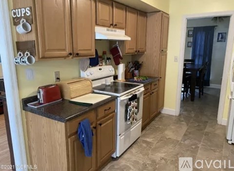 A kitchen with wooden cabinets and a white stove top oven.