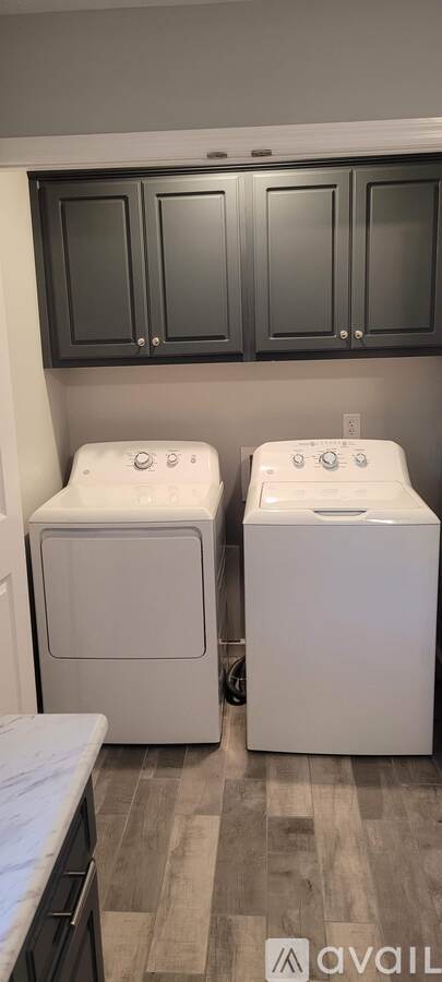 Two white washing machines in front of a wall.