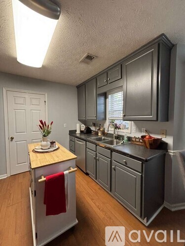 A kitchen with a white door and a red towel hanging on the oven.