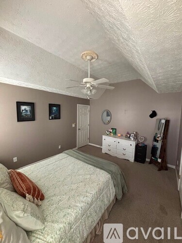 A bedroom with a bed, dresser, and ceiling fan.