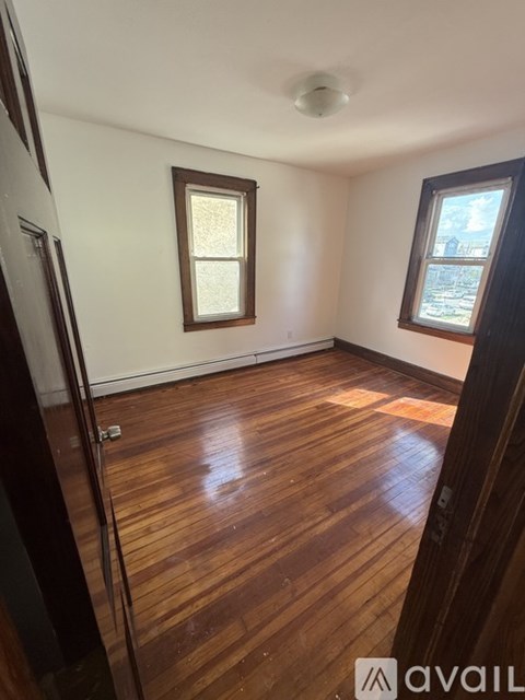 A room with wooden floors and two windows.